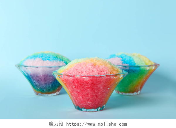 蓝色背景墙的冰沙浅蓝色背景玻璃甜点碗中的彩虹剃须刀冰